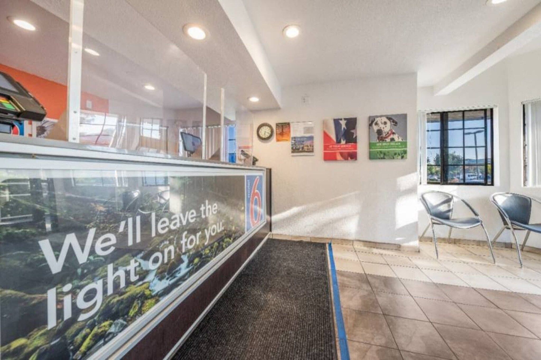 A reception area with a glass partition, a clock, and a window with a view.