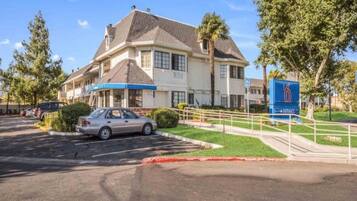A two-story building with a parking lot and a blue sign indicating a location.