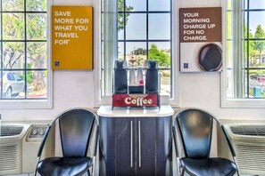 Una habitación con dos sillas negras, un espacio para café y carteles motivacionales en las paredes.