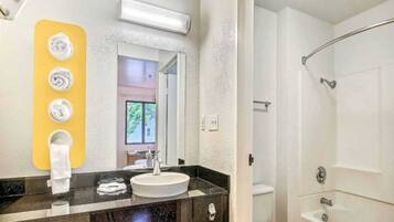 A bathroom with a sink, mirror, towel rack, and shower.