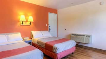 A hotel room with two beds, a nightstand, a lamp, an air conditioning unit, and a door.