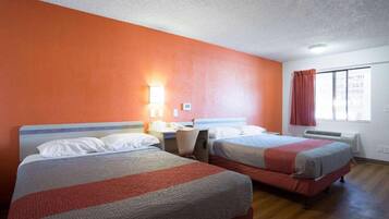 A hotel room with two beds, a nightstand, a lamp, and a window with curtains.