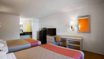 Quarto de hotel com duas camas, uma escrivaninha, uma cadeira, uma televisão e um espelho.