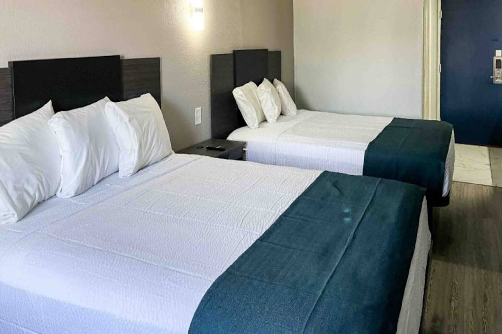 Zwei Betten mit weißer Bettwäsche und dunklen Kopfteilen in einem Hotelzimmer.