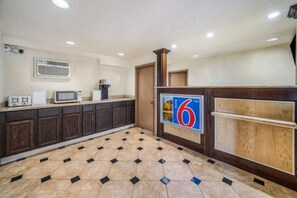 Habitación de hotel con kitchenette, piso de baldosas y un gran letrero con el número 6 en la pared.