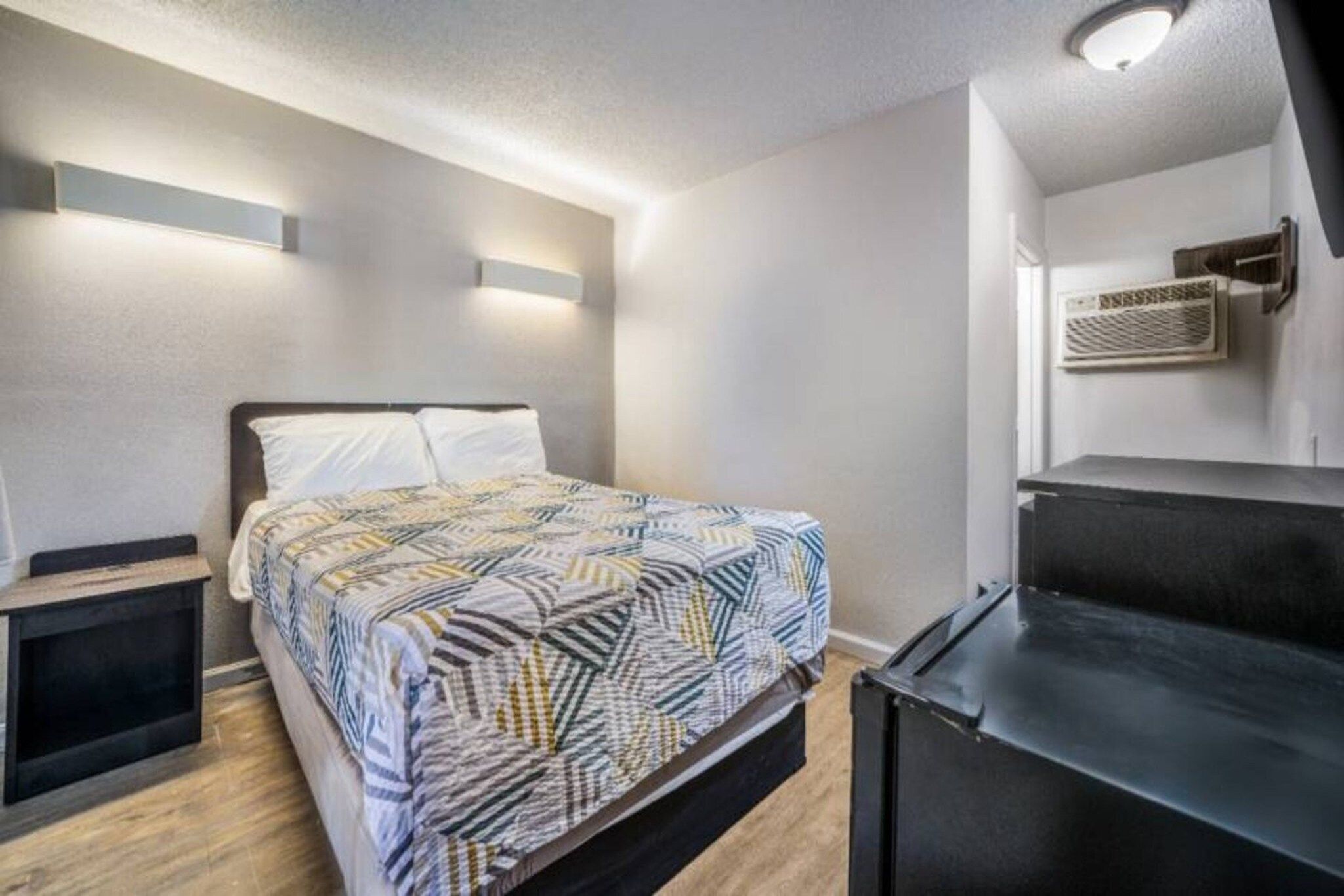 A modern bedroom with a bed, bedside tables, and a built-in bench.