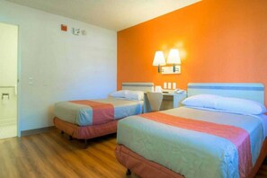 Ein Hotelzimmer mit zwei Betten, einem Schreibtisch und einem Stuhl.