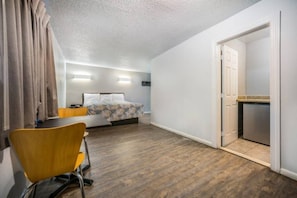 Ein Hotelzimmer mit Bett, Schreibtisch, Stuhl und einer Küchenzeile.