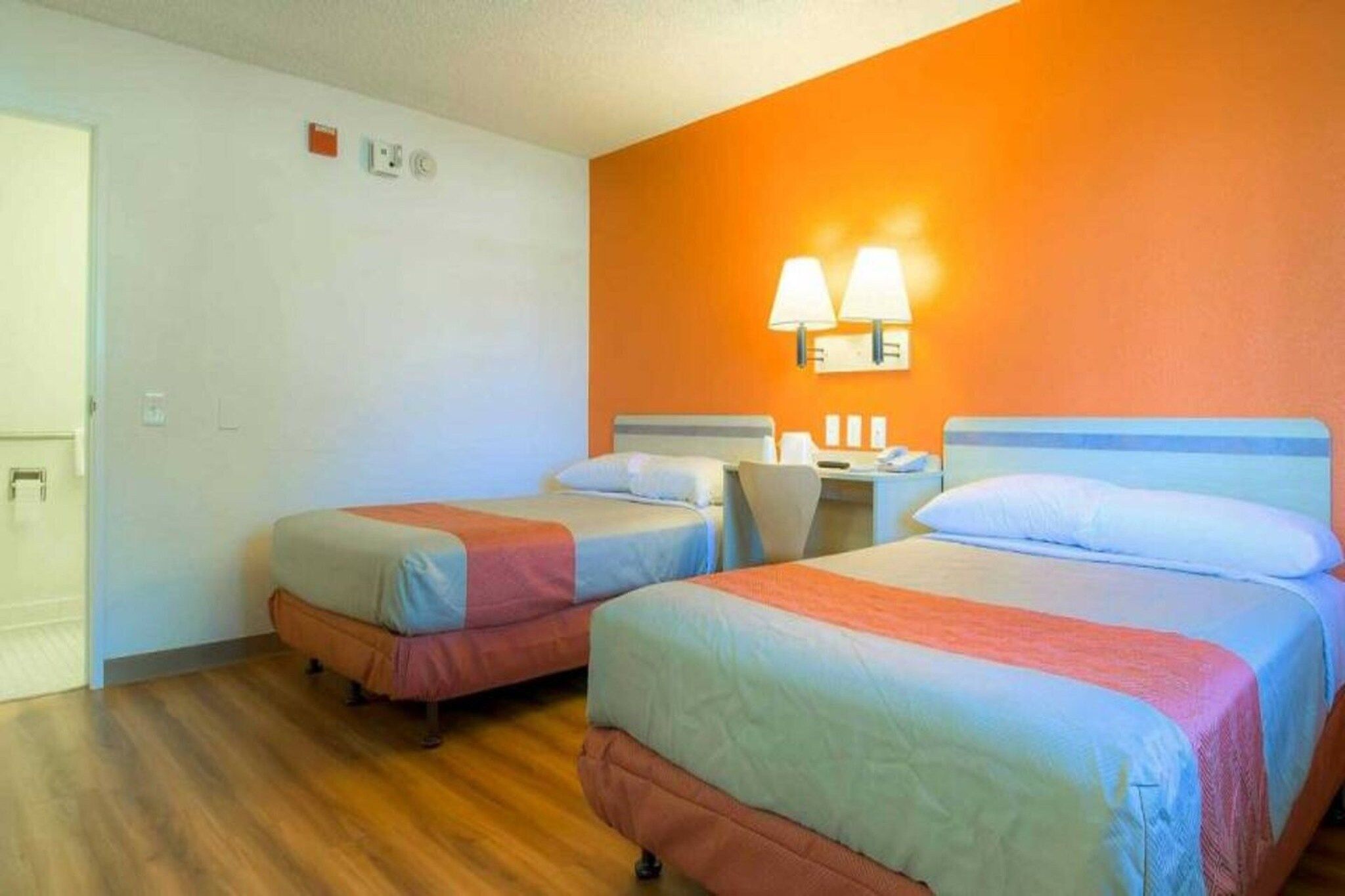 Ein Hotelzimmer mit zwei Betten, einem Schreibtisch und einem Stuhl.