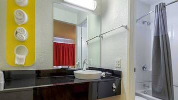 A bathroom with a sink, mirror, and shower.