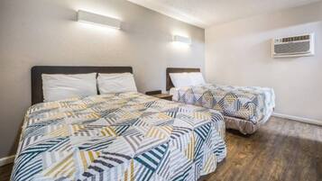 Ein Hotelzimmer mit zwei Betten, Holzboden und einer Wand-Klimaanlage.