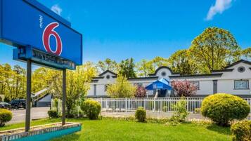 A motel with a prominent '6' sign, a fenced parking area, and a building with a modern design.