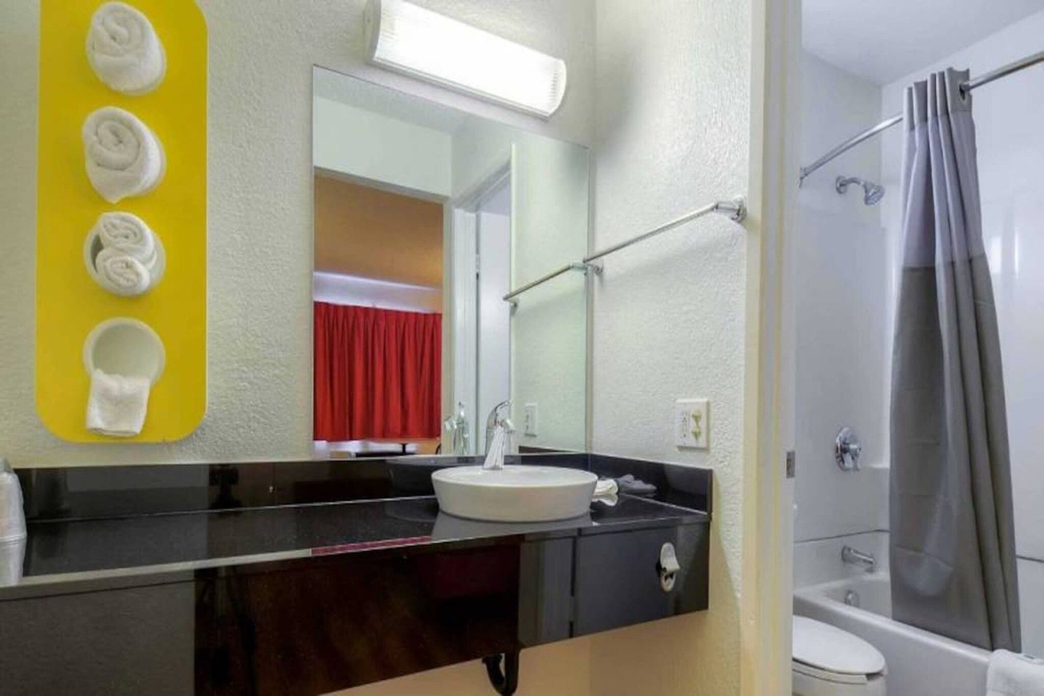 A bathroom with a sink, mirror, and shower.