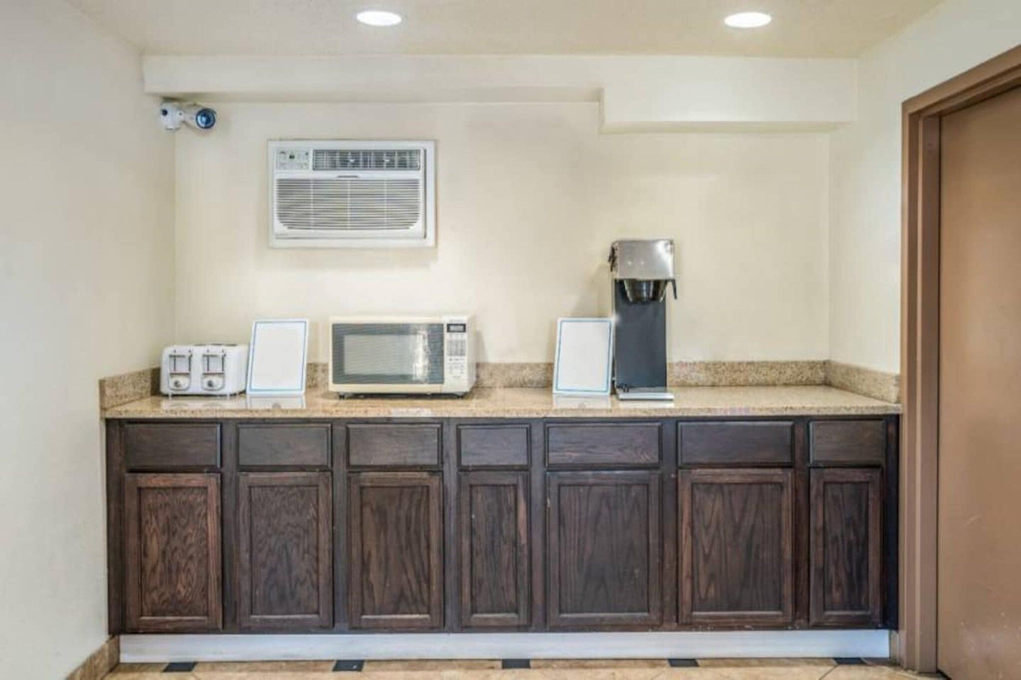 Una cocina con microondas, tostadora y cafetera sobre la encimera.