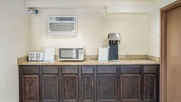 Una cocina con microondas, tostadora y cafetera sobre la encimera.