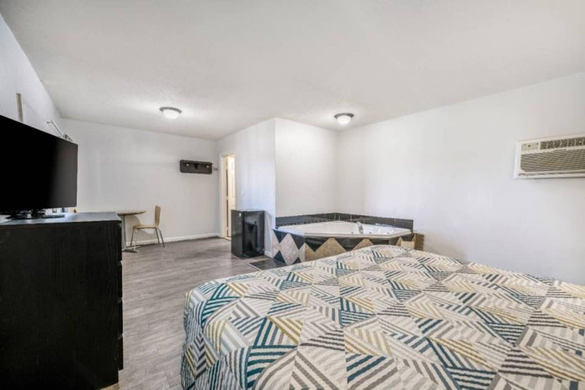Una habitación de hotel con cama, escritorio, silla, televisión y baño.