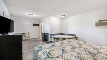 Una habitación de hotel con cama, escritorio, silla, televisión y baño.