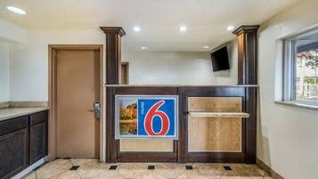 Ein Hotel-Empfangsbereich mit einem großen Schild mit der Zahl 6, einem hölzernen Empfangstresen, einer Tür und einem gefliesten Boden.