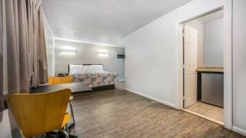 Ein Hotelzimmer mit Bett, Schreibtisch, Stuhl und einer Küchenzeile.