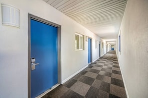 A hotel corridor with blue doors, checkered carpet, and white walls.