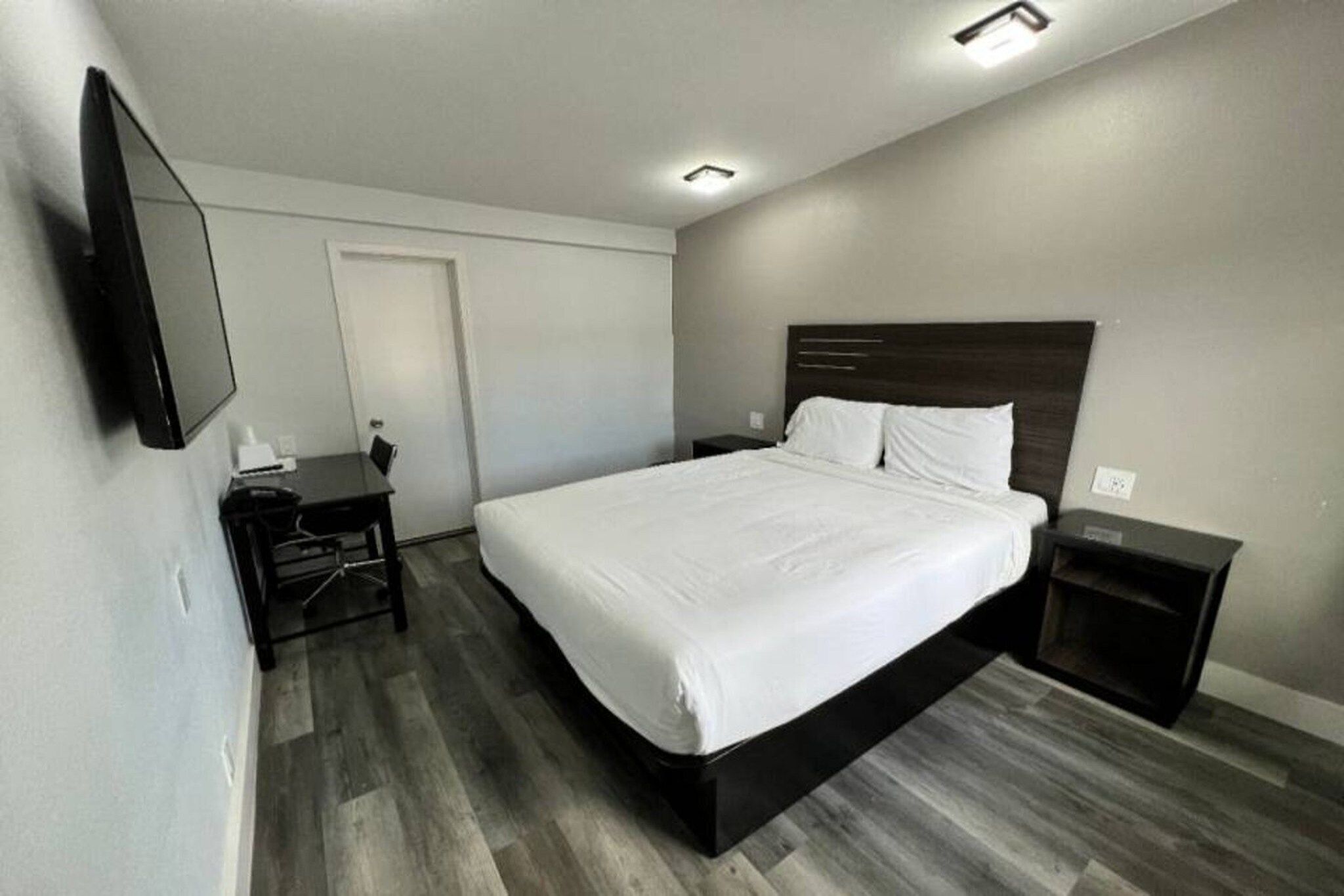 Ein Hotelzimmer mit Bett, Nachttisch und Schreibtisch mit Stuhl.