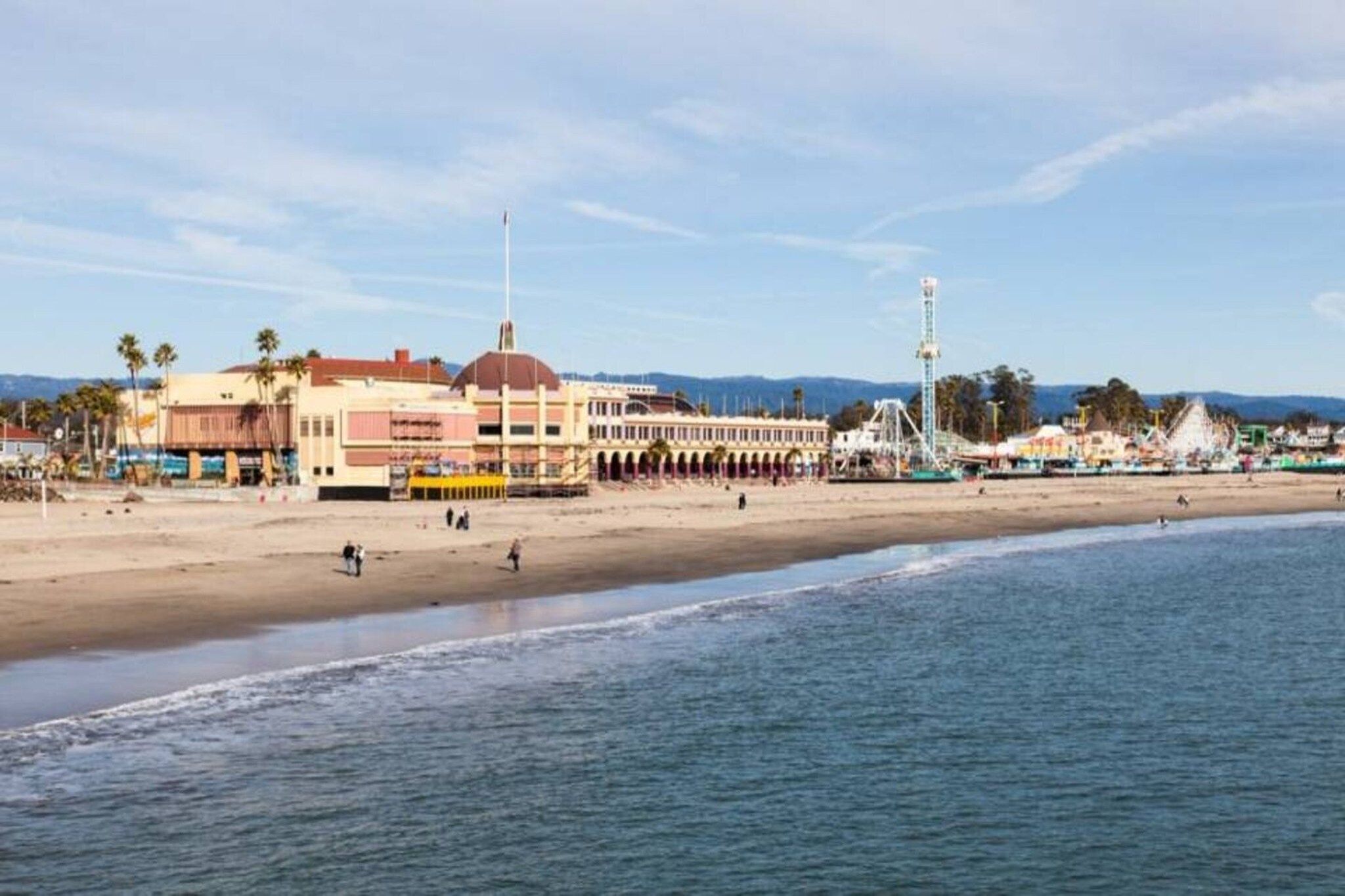 A beach with a row of buildings, including a hotel with a large balcony overlooking the sea.