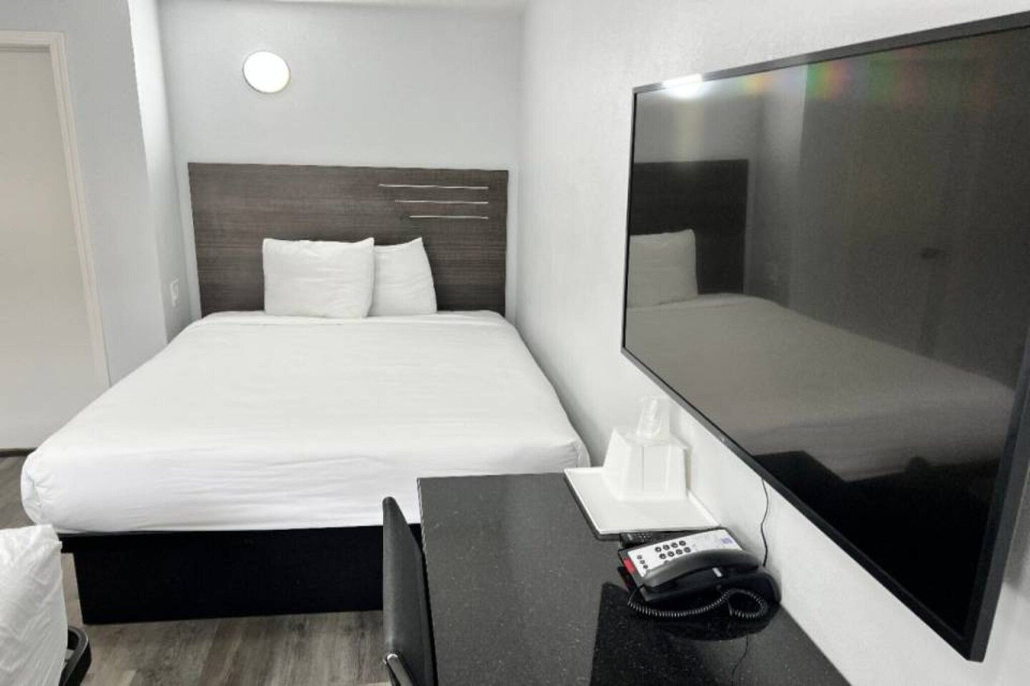 A hotel room with a bed, bedside table, and a large mirror.