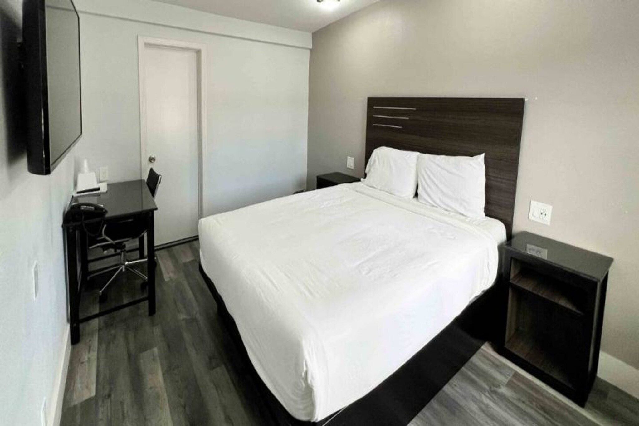 Une chambre d’hôtel avec un grand lit, un bureau, une chaise et un téléviseur.