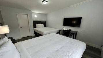 Habitación de hotel con dos camas, televisor, escritorio y una puerta.