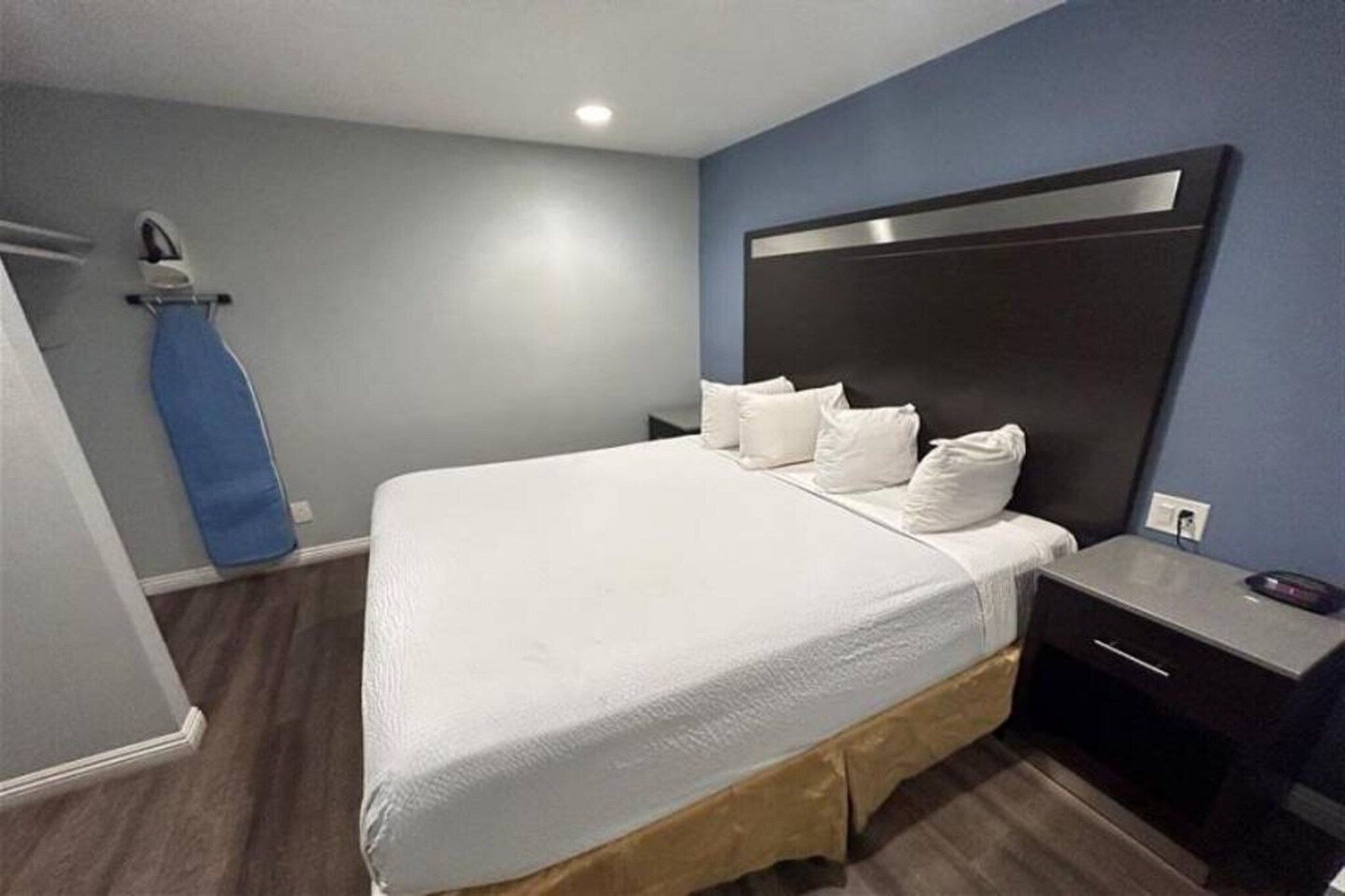Een hotelkamer met een groot bed, een nachtkastje en een bureau met een computer.