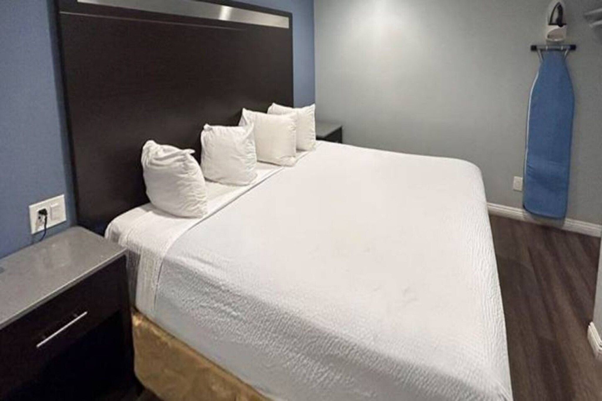 A hotel room with a bed, a nightstand, and a blue curtain.