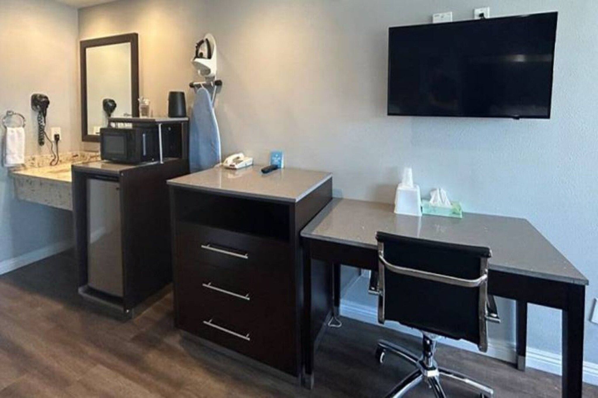 Een moderne badkamer met een wastafel, spiegel en een flatscreen televisie aan de wand.