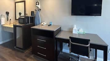 Een moderne badkamer met een wastafel, spiegel en een flatscreen televisie aan de wand.