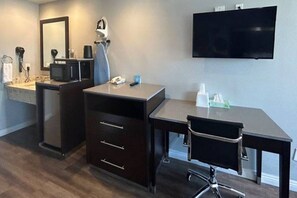 Een moderne badkamer met een wastafel, spiegel en een flatscreen televisie aan de wand.