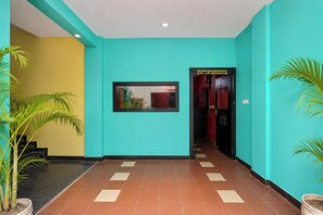 Un pasillo con paredes color turquesa, un cuadro enmarcado y plantas en macetas.