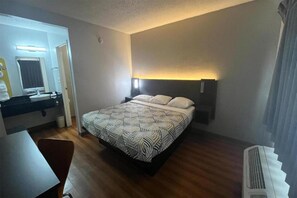 A hotel room with a bed, bedside table, and a bathroom visible through an open door. - 1 King Bed|NS | Modesto (Modesto)