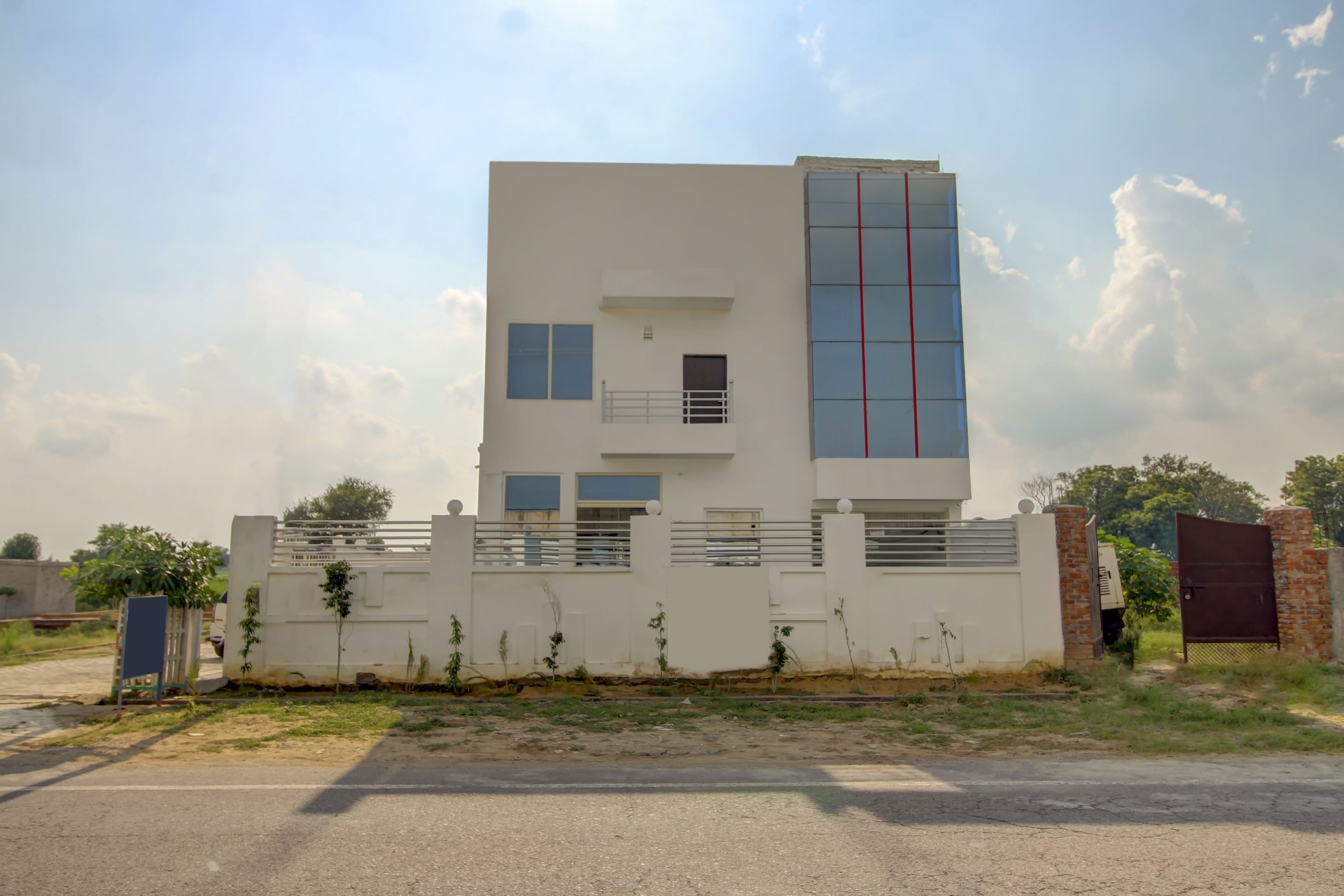 Un edificio moderno de dos plantas con techo plano, un balcón y un gran ventanal.