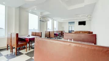 Ein Restaurant mit Sitzbänken und Tischen, großen Fenstern und einem Flachbildfernseher an der Wand.