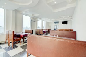 Un restaurante con cabinas y mesas, amplias ventanas y un televisor de pantalla plana en la pared.