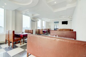 Un restaurante con cabinas y mesas, amplias ventanas y un televisor de pantalla plana en la pared.