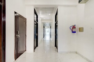 Pasillo de hotel con puertas a ambos lados, un extintor de incendios en la pared y un piso de baldosas limpio.