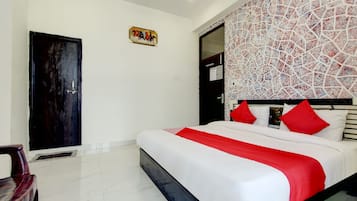A hotel room with a bed, a door, a wall with a mosaic pattern, and a small painting on the wall.