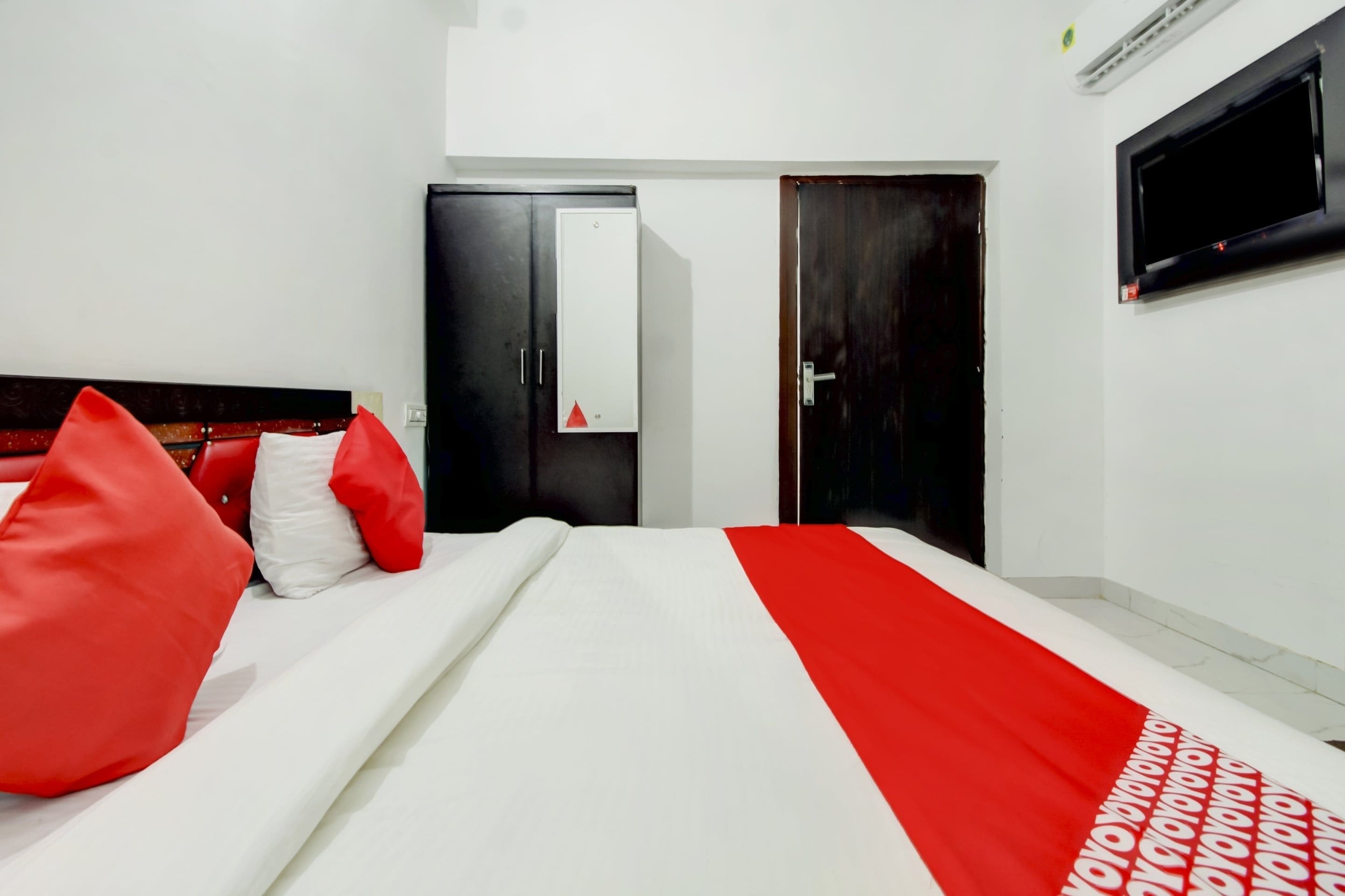 A hotel room with a bed, a wardrobe, a mirror, and a television.