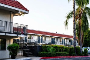 Un motel con techo rojo, varios balcones y una zona de estacionamiento.