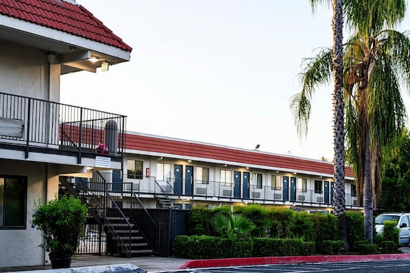 Un motel con techo rojo, varios balcones y una zona de estacionamiento.