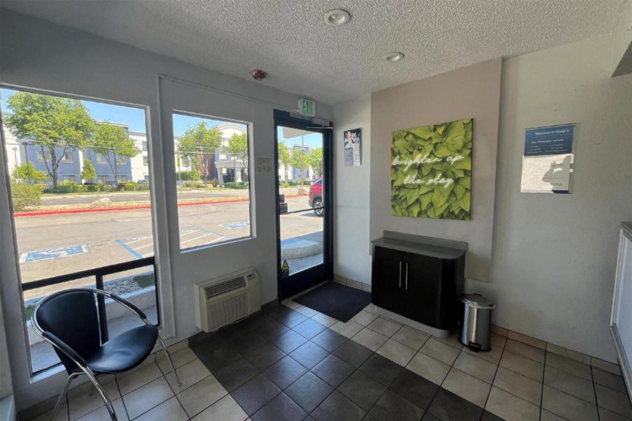 A reception area with a chair, a cabinet, and a trash bin.