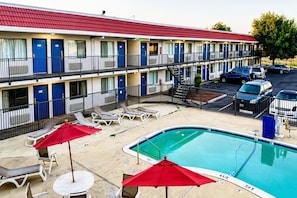 Un motel con piscina, asientos al aire libre y zona de estacionamiento.