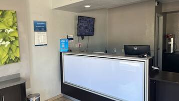 A reception desk with a computer, a monitor, and a signboard.