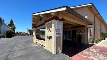 A building with a covered parking area and a sign indicating customer parking only.