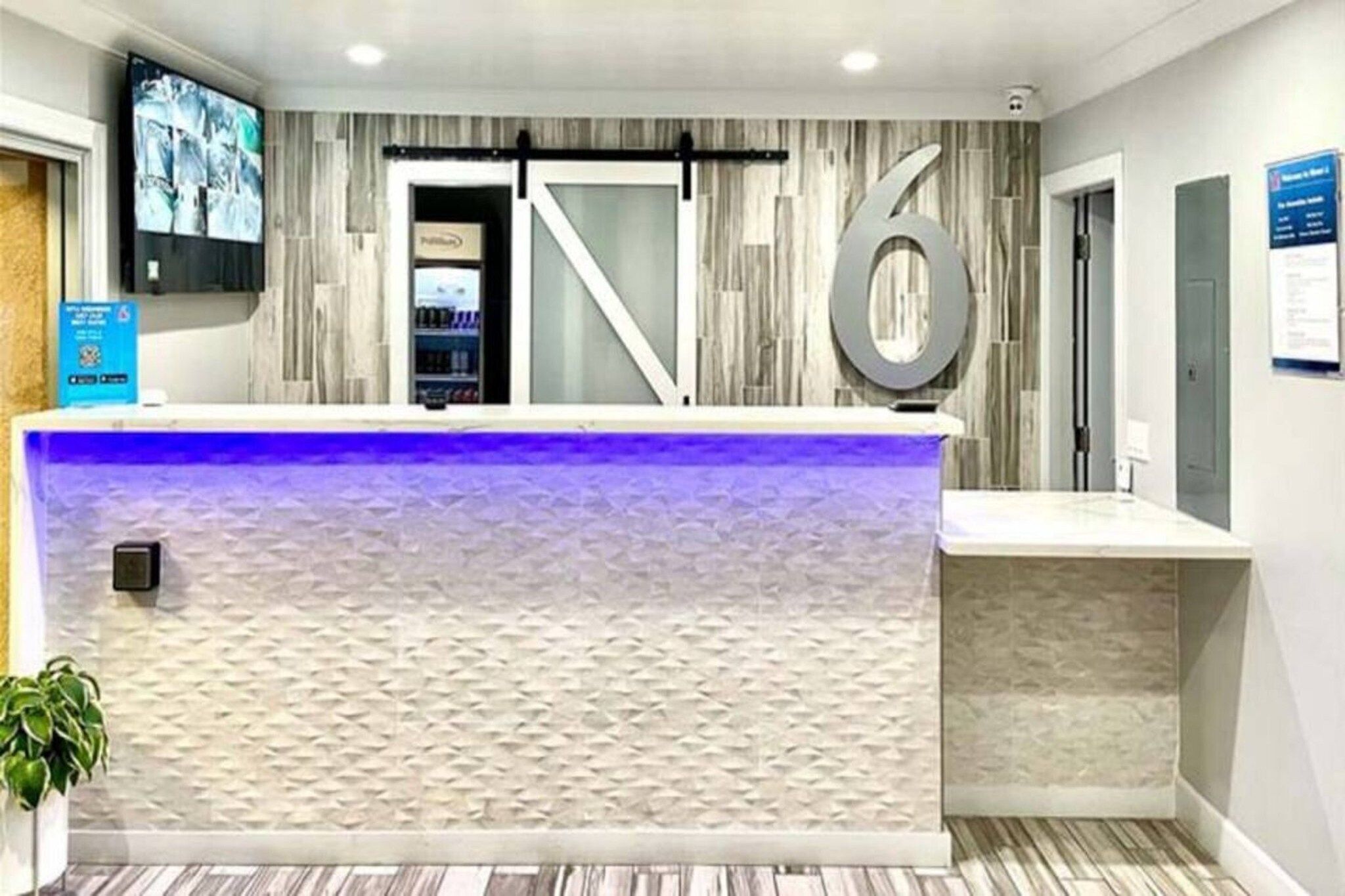 A reception desk with a modern design, a large number '6' sign, and a television mounted on the wall.